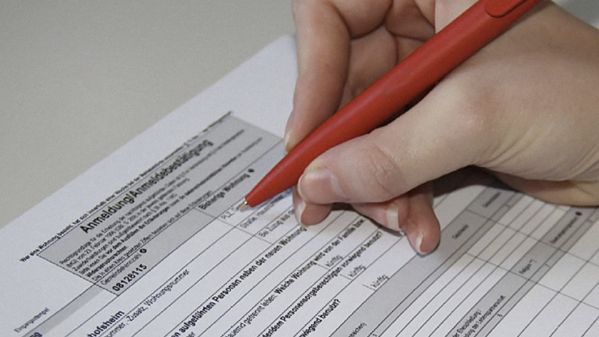 Person füllt ein Formular mit einem roten Stift aus